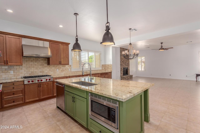 kitchen with sink, stainless steel appliances, green cabinets, ventilation hood, and an island with sink