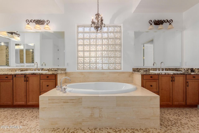 bathroom with a relaxing tiled tub, vanity, and an inviting chandelier