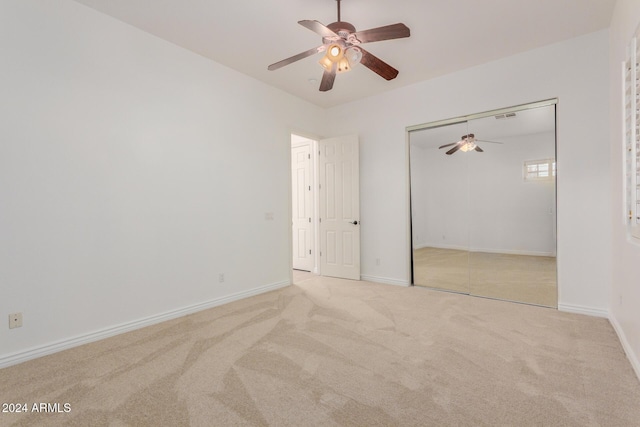 unfurnished bedroom with a closet, light colored carpet, and ceiling fan