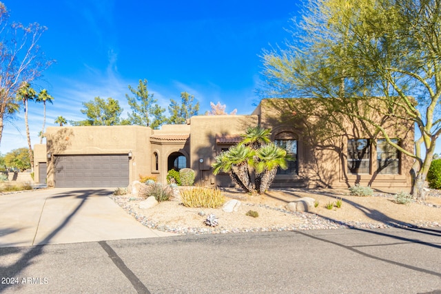 pueblo revival-style home featuring a garage