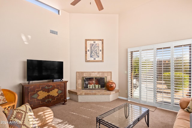 carpeted living room featuring a high ceiling, ceiling fan, and a fireplace