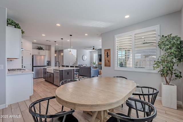 dining space featuring ceiling fan, sink, and light hardwood / wood-style floors