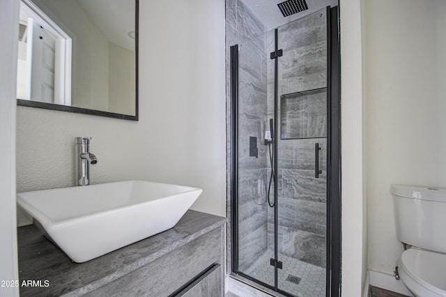 bathroom with toilet, a shower with door, and sink