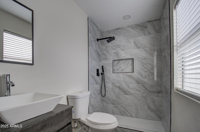 bathroom with toilet, vanity, and tiled shower