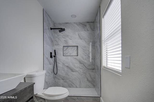 bathroom featuring vanity, toilet, and tiled shower