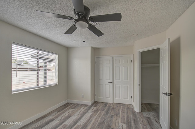 unfurnished bedroom featuring ceiling fan, light wood-type flooring, and a textured ceiling