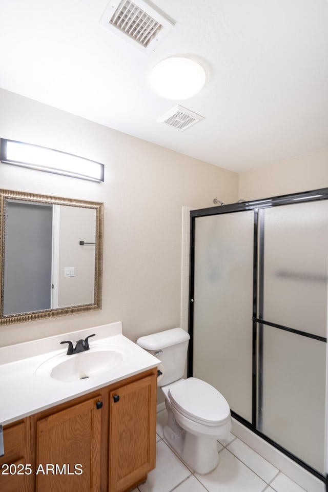 bathroom with tile patterned flooring, vanity, toilet, and a shower with shower door