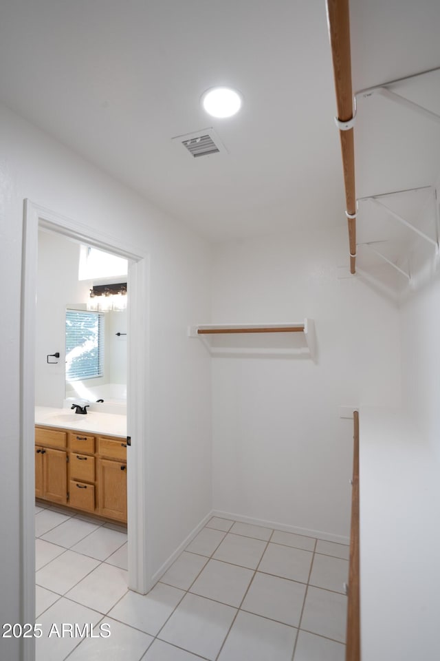 walk in closet featuring sink and light tile patterned floors