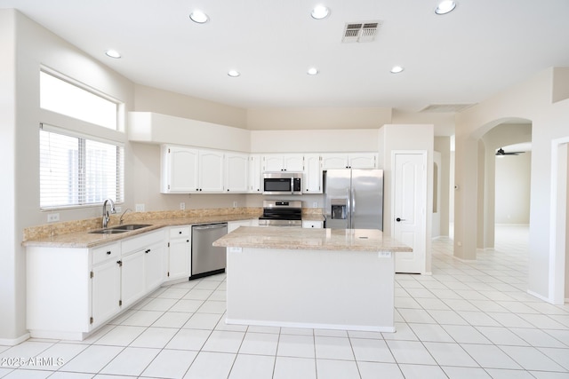 kitchen with light tile patterned flooring, sink, a center island, stainless steel appliances, and white cabinets