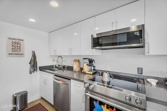 4411 N 40th St Unit 59, Phoenix, AZ 85018 - kitchen featuring stainless steel appliances, a sink, dark countertops, white cabinets, and backsplash
