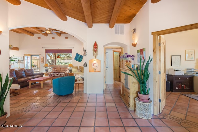 tiled living room featuring beam ceiling, wood ceiling, ceiling fan, and a high ceiling