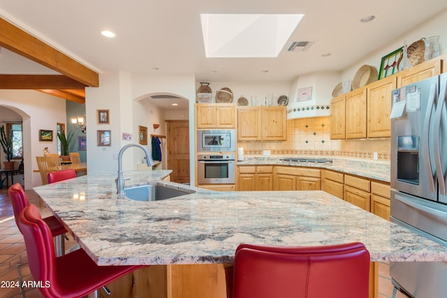 kitchen with stainless steel appliances, a kitchen bar, and a center island with sink