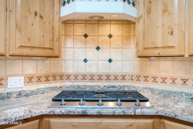 interior details with light stone countertops, light brown cabinetry, stainless steel gas cooktop, and decorative backsplash