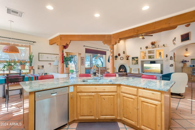 kitchen featuring sink, dishwasher, hanging light fixtures, light stone counters, and a center island with sink