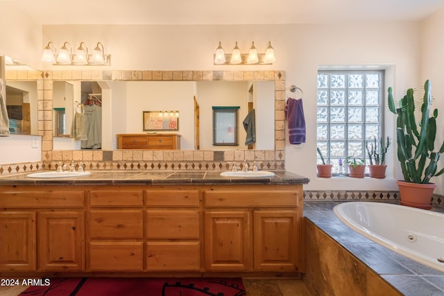 bathroom featuring vanity, a relaxing tiled tub, tasteful backsplash, and a healthy amount of sunlight