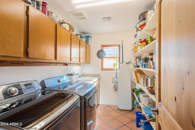 washroom with light tile patterned floors, sink, washer and clothes dryer, and cabinets