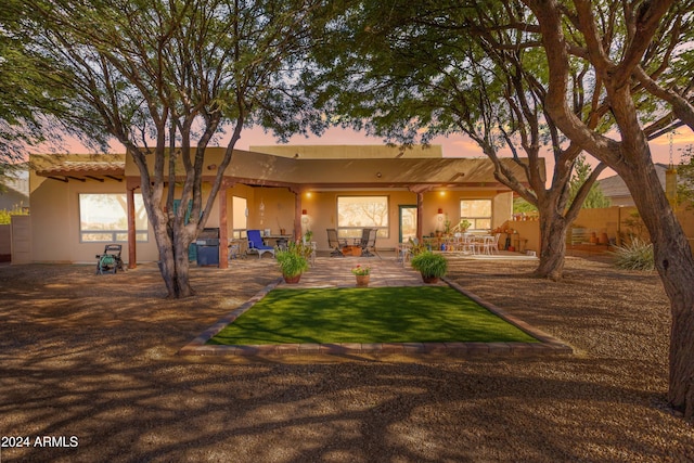 back house at dusk featuring a patio