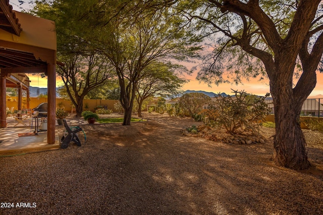 yard at dusk featuring a mountain view and a patio area