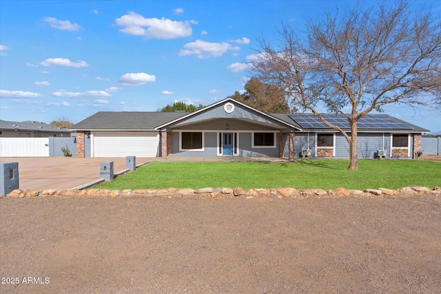 ranch-style house with a garage, covered porch, solar panels, and a front yard