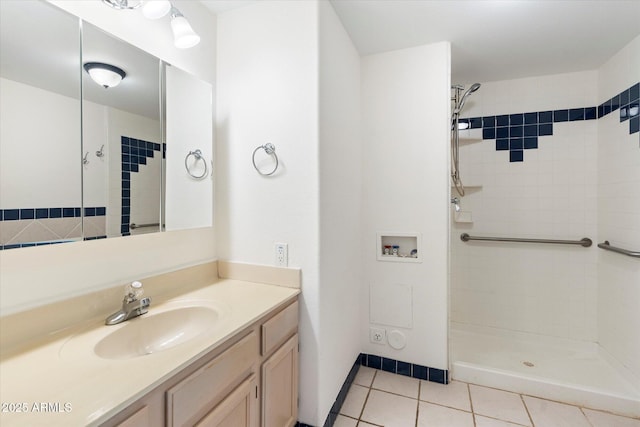 bathroom featuring tiled shower, tile patterned flooring, and vanity