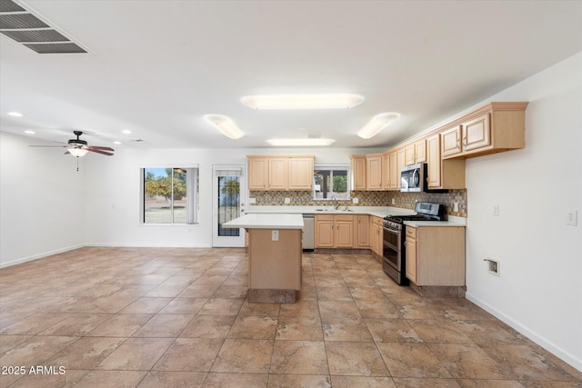 kitchen with light brown cabinetry, plenty of natural light, appliances with stainless steel finishes, and a kitchen island