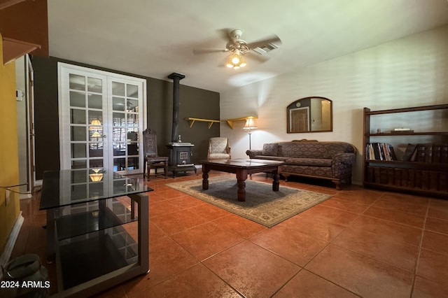 tiled living area featuring ceiling fan, visible vents, and a wood stove