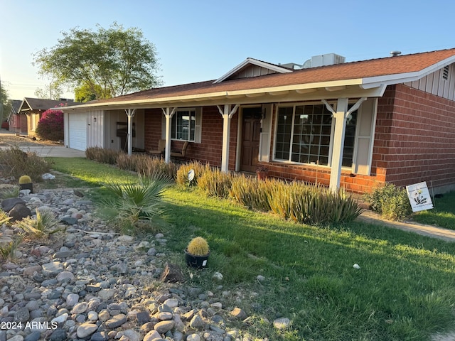 single story home with covered porch, a garage, and a front lawn