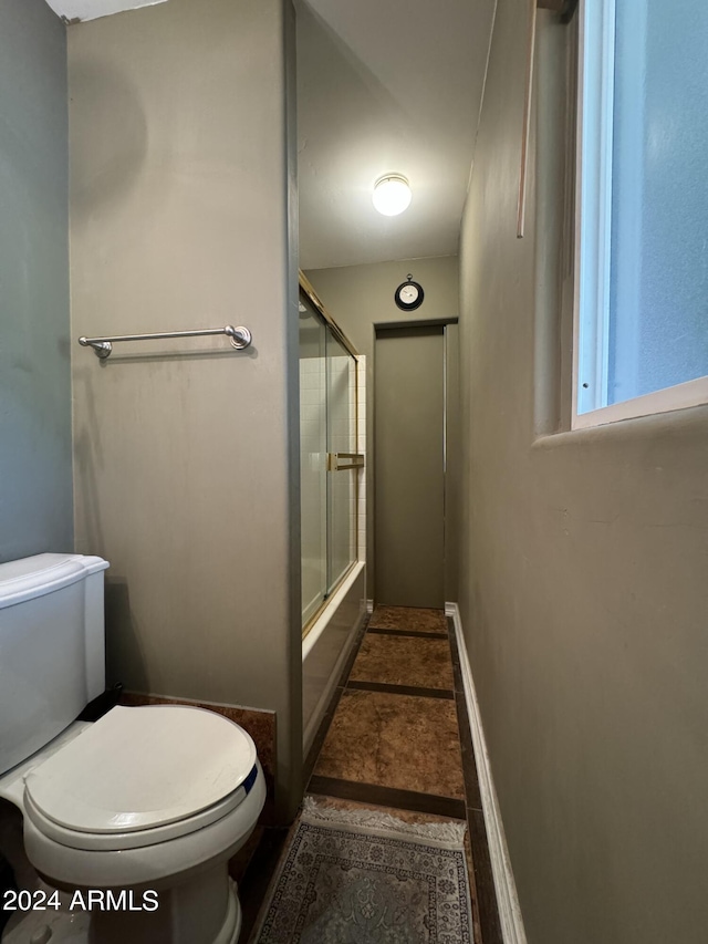 full bath with baseboards, shower / bath combination with glass door, and toilet
