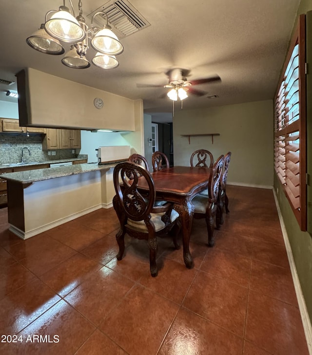 dining space featuring baseboards, visible vents, ceiling fan, and dark tile patterned flooring