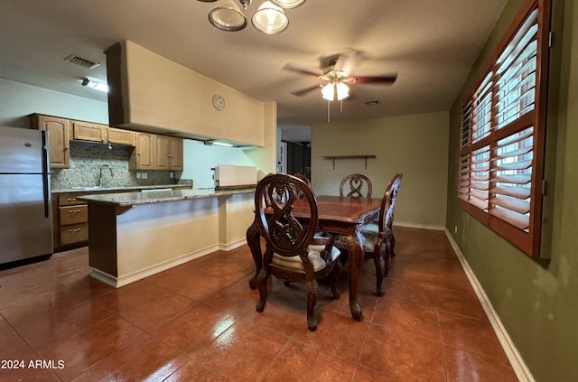 dining room featuring ceiling fan, dark tile patterned floors, and sink