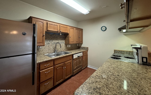 kitchen with a sink, tasteful backsplash, dishwasher, dark tile patterned floors, and freestanding refrigerator
