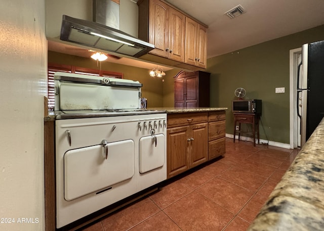 kitchen with black fridge, dark tile patterned flooring, and range hood