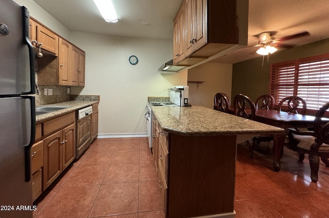 kitchen with ceiling fan, stainless steel appliances, tasteful backsplash, tile patterned floors, and a breakfast bar area