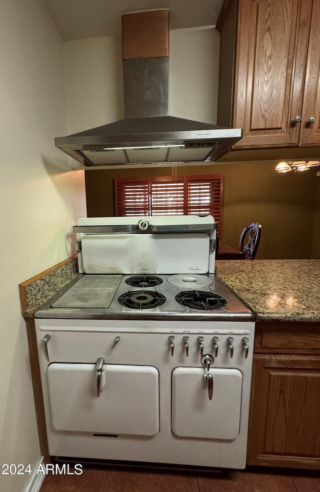 kitchen featuring electric stove, tile patterned flooring, brown cabinets, ventilation hood, and stone countertops