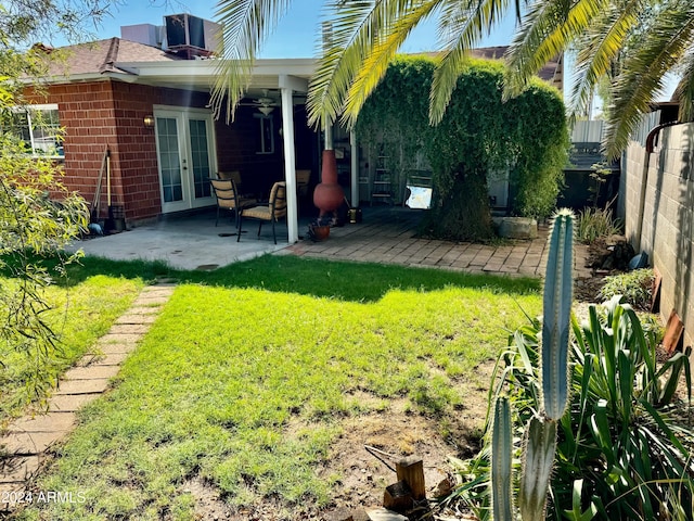 view of yard featuring fence, french doors, central AC unit, and a patio area