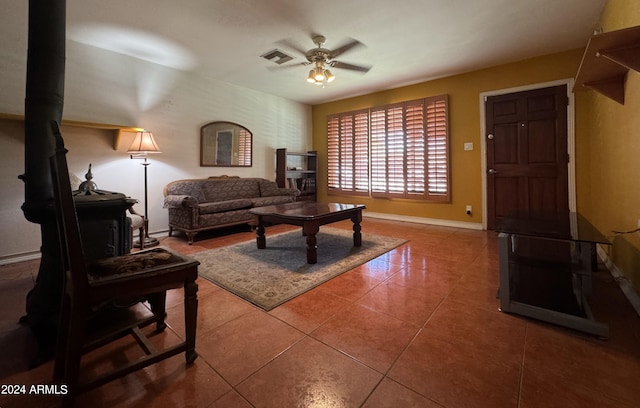 living room featuring a wood stove, ceiling fan, and tile patterned flooring