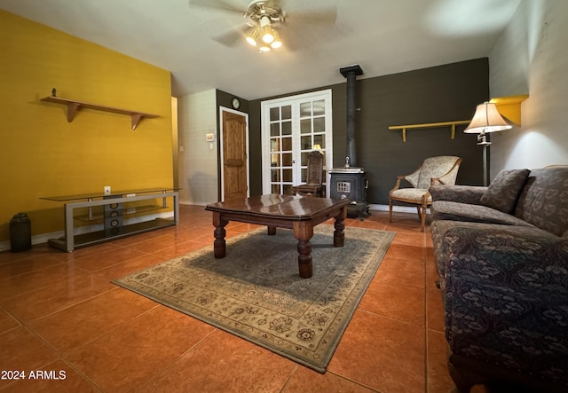 living room featuring tile patterned floors, a wood stove, ceiling fan, and french doors