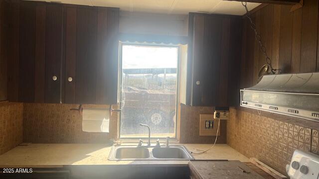 kitchen featuring a sink, under cabinet range hood, stove, and tasteful backsplash