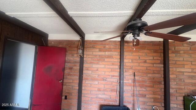 detailed view of ceiling fan, brick wall, and beam ceiling