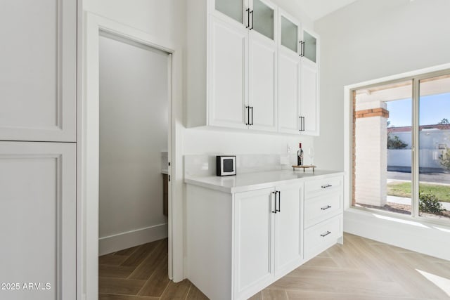 bar featuring white cabinets and light parquet floors