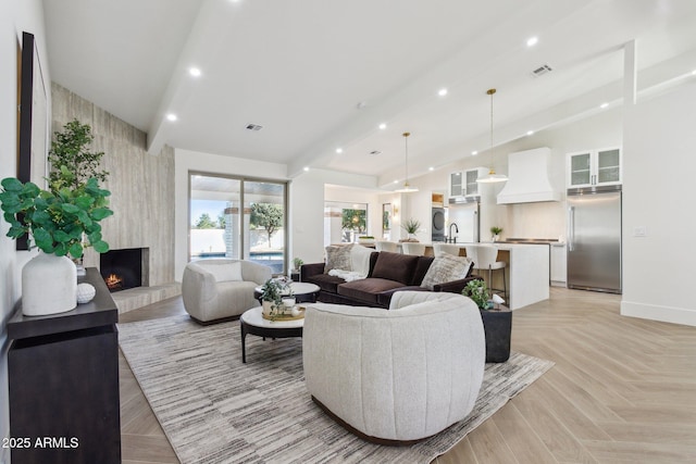 living room with vaulted ceiling with beams, a fireplace, sink, and light parquet floors