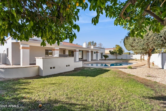 rear view of property featuring a fenced in pool, an outdoor kitchen, and a lawn