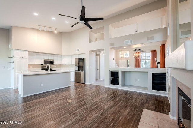 1227 E Sheena Dr, Phoenix, AZ 85022 - unfurnished living room featuring ceiling fan, a sink, a high ceiling, a tiled fireplace, and wood finished floors