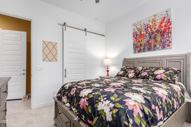 carpeted bedroom with a barn door and ceiling fan