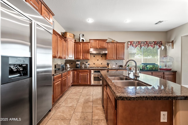 2565 N 141st Ln, Goodyear, AZ 85395 - kitchen with appliances with stainless steel finishes, a sink, under cabinet range hood, a kitchen island with sink, and backsplash