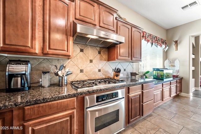 2565 N 141st Ln, Goodyear, AZ 85395 - kitchen featuring stainless steel appliances, under cabinet range hood, tasteful backsplash, and brown cabinetry