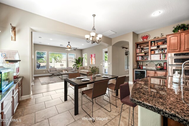 2565 N 141st Ln, Goodyear, AZ 85395 - dining room featuring wine cooler, arched walkways, baseboards, a ceiling fan, and a chandelier