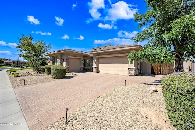 2565 N 141st Ln, Goodyear, AZ 85395 - prairie-style house with a garage, decorative driveway, stone siding, fence, and stucco siding