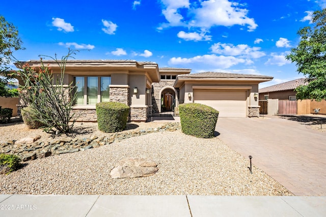 2565 N 141st Ln, Goodyear, AZ 85395 - prairie-style house featuring stone siding, driveway, a garage, stucco siding, and fence