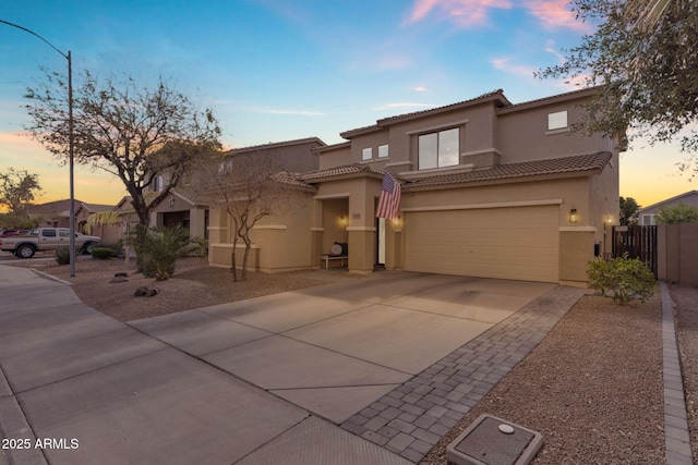 view of front of property featuring stucco siding, driveway, fence, a garage, and a tiled roof